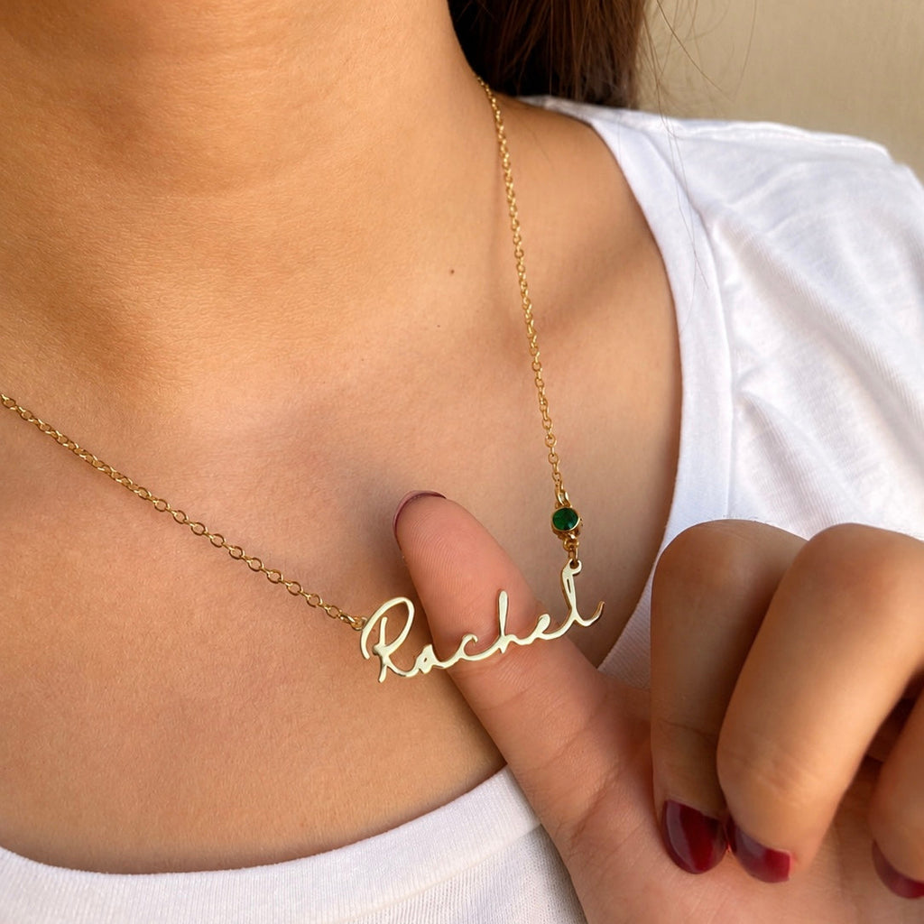 Gold necklace with 'Rachel' pendant on a person wearing a white top.