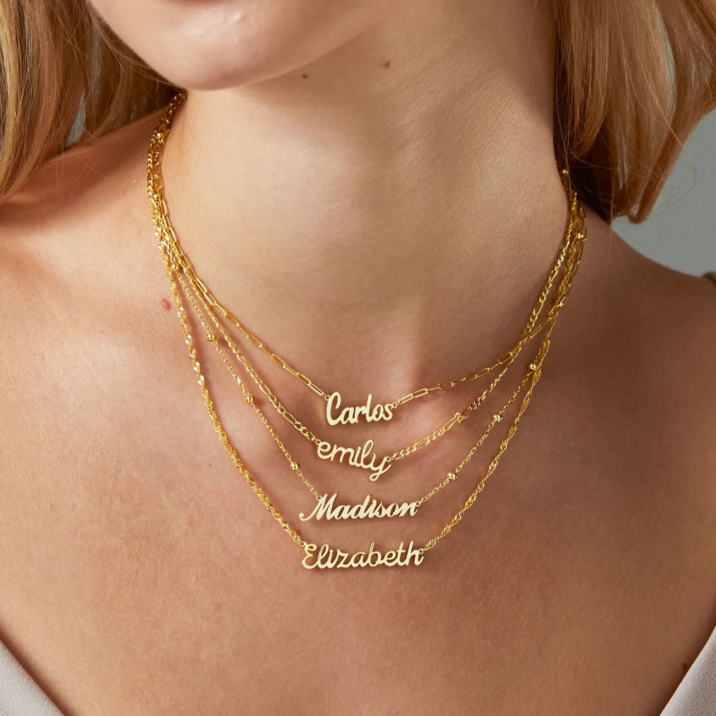 Gold name necklaces on a person's neck with names 'Carlos', 'Emily', 'Madison', and 'Elizabeth'.