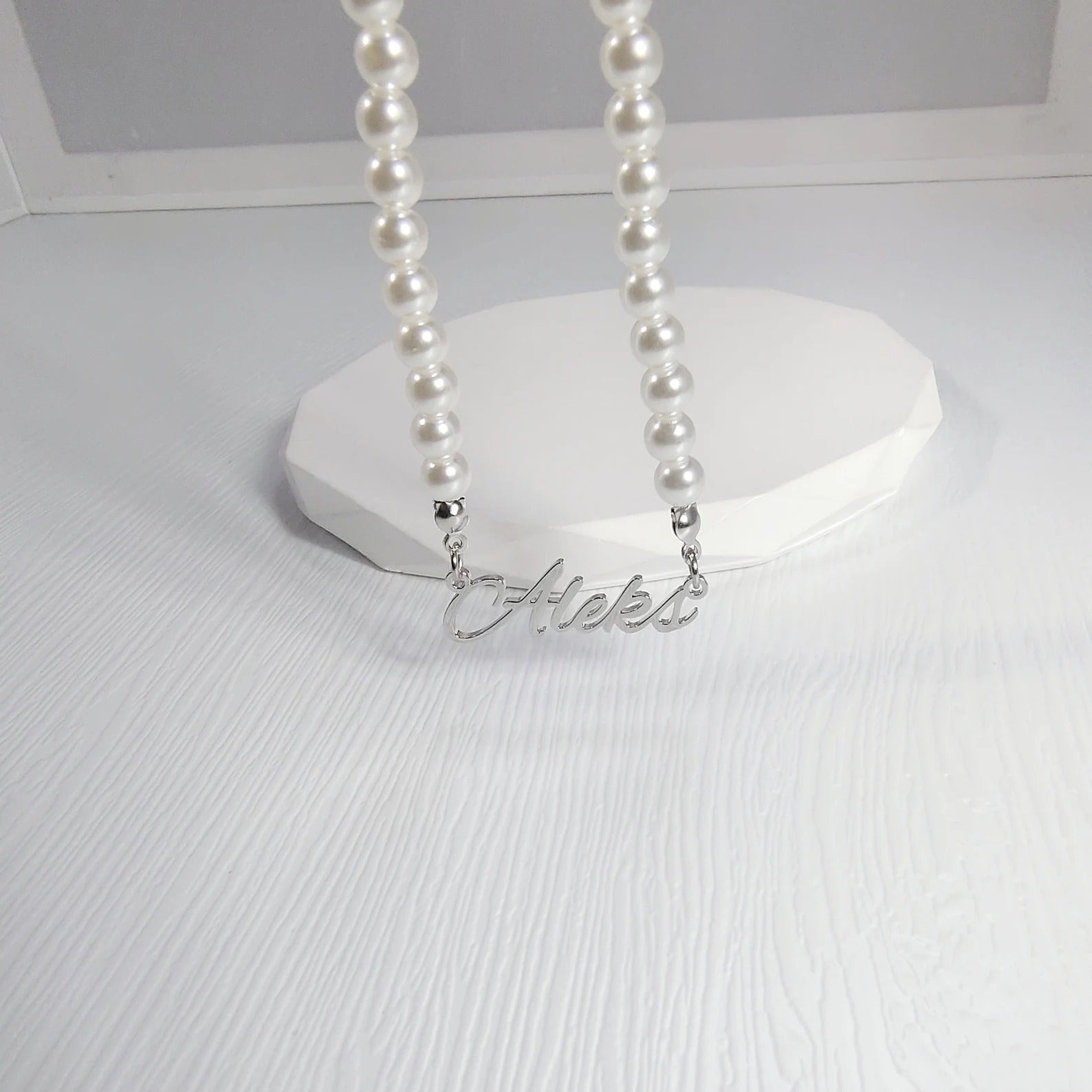 Pearl necklace with a silver 'Helen' pendant on a white stand.