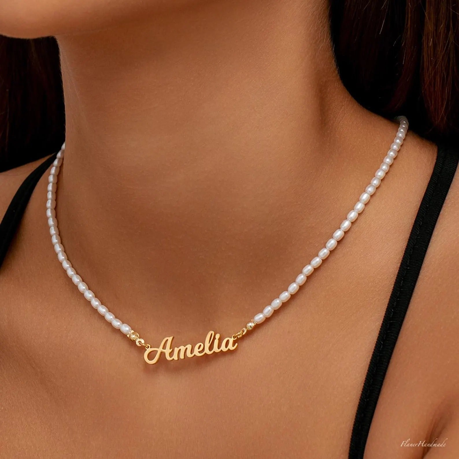 Pearl necklace with a gold 'Amelia' pendant on a person wearing a black top.
