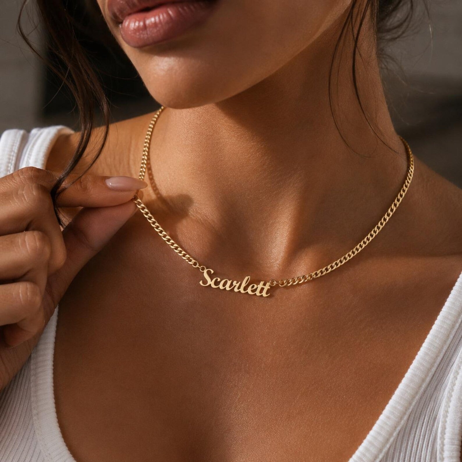 Gold necklace with 'Scarlett' pendant on a person wearing a white top.